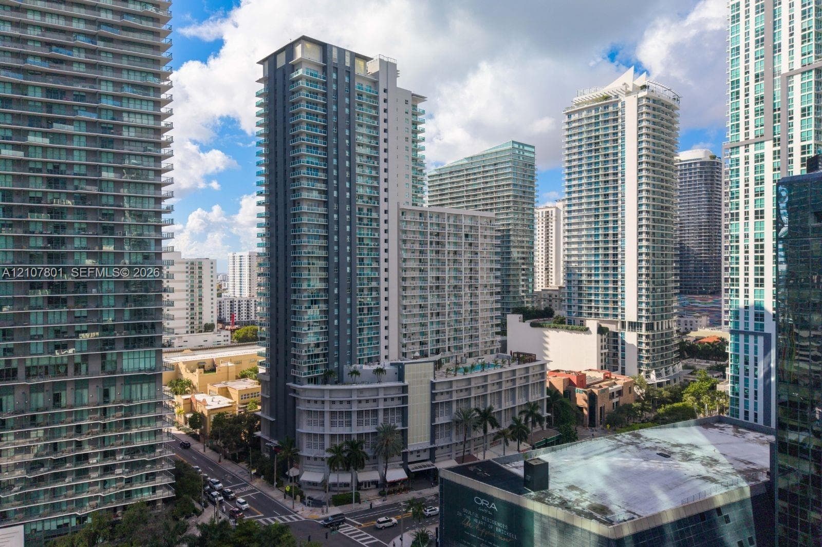 High-rise residential tower featuring glass balcony railings, floor-to-ceiling windows, and a structured multi-level podium