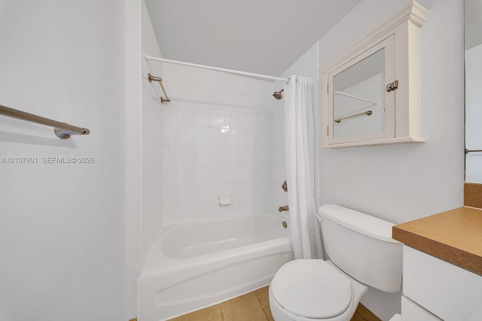 Bathroom featuring a white bathtub with tile surround, built-in medicine cabinet with integrated mirror, and metallic hardware finish