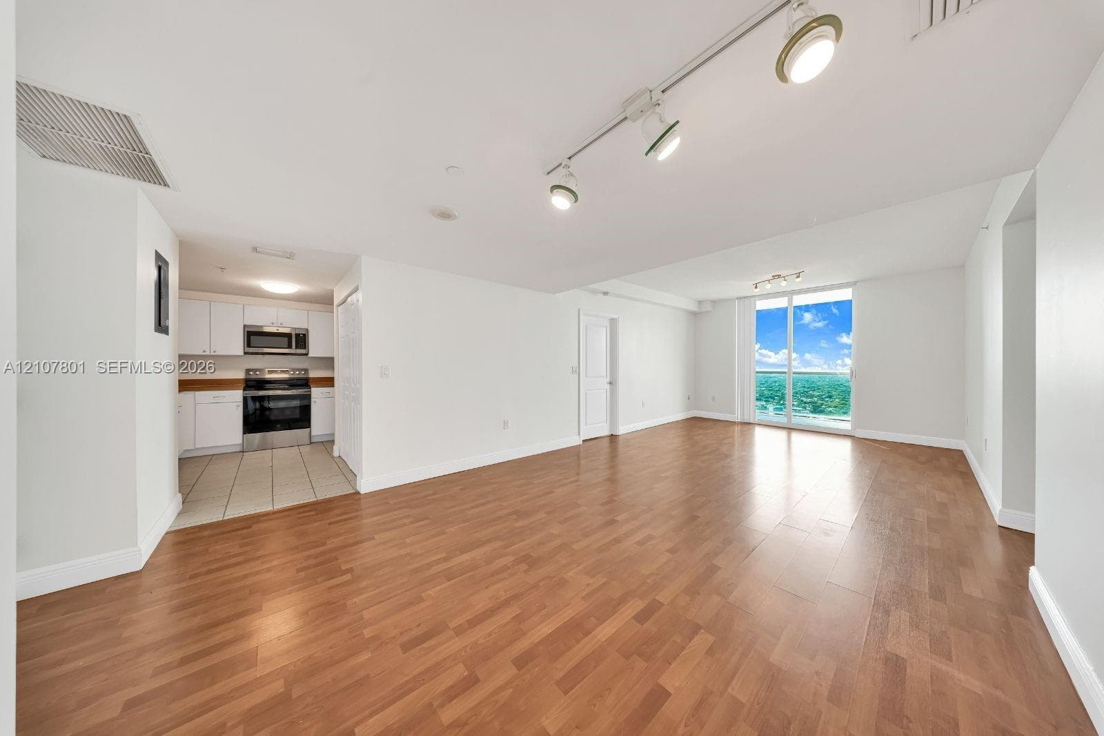 Open interior space featuring wood-finish flooring, track lighting, and floor-to-ceiling glass sliding doors