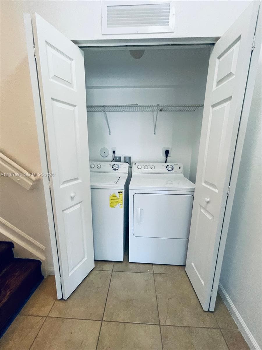 Laundry closet featuring double bi-fold doors, white top-loading washer and dryer, and a wire shelving unit