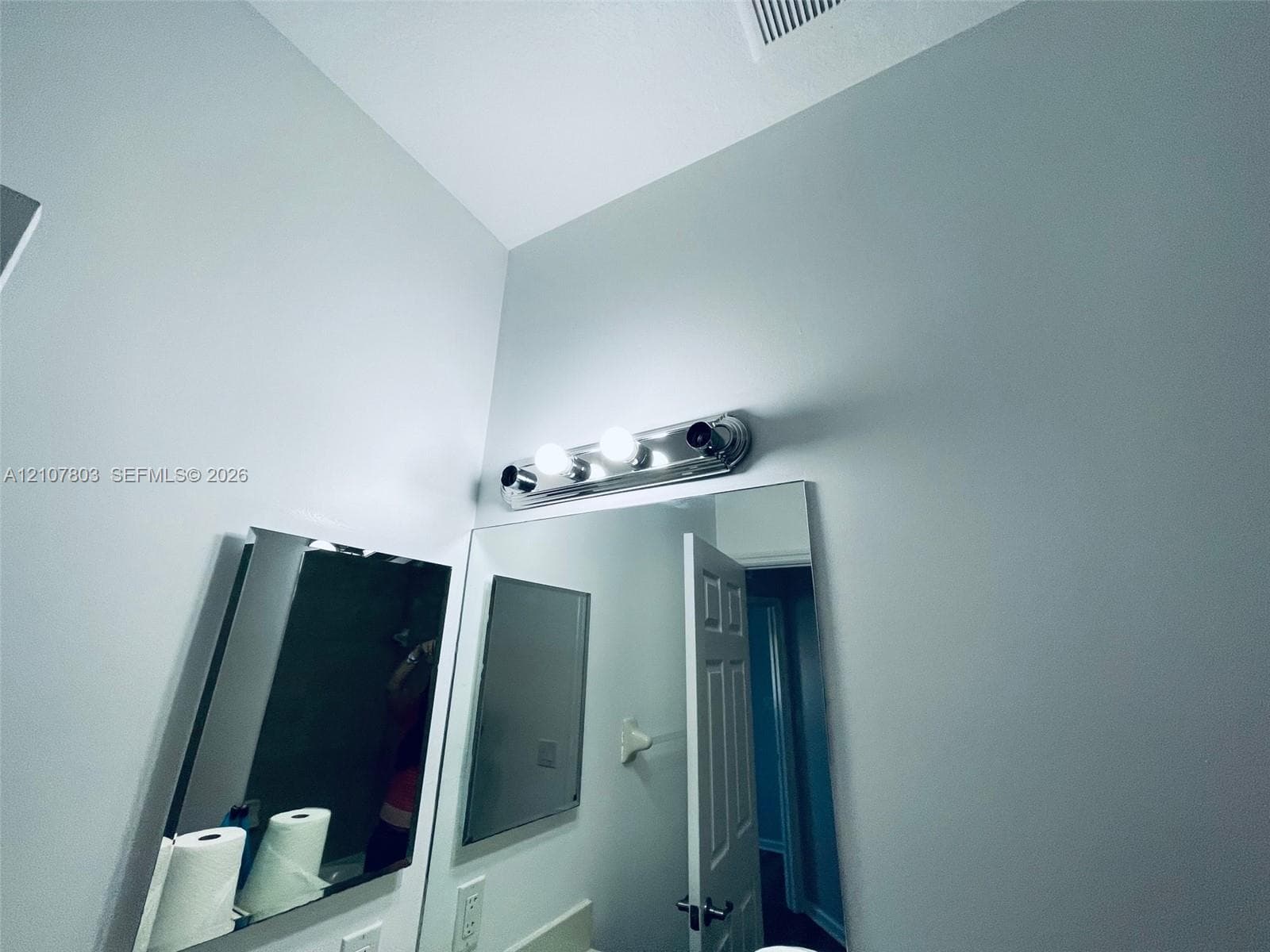Large frameless mirror accented by a three-light polished chrome vanity fixture