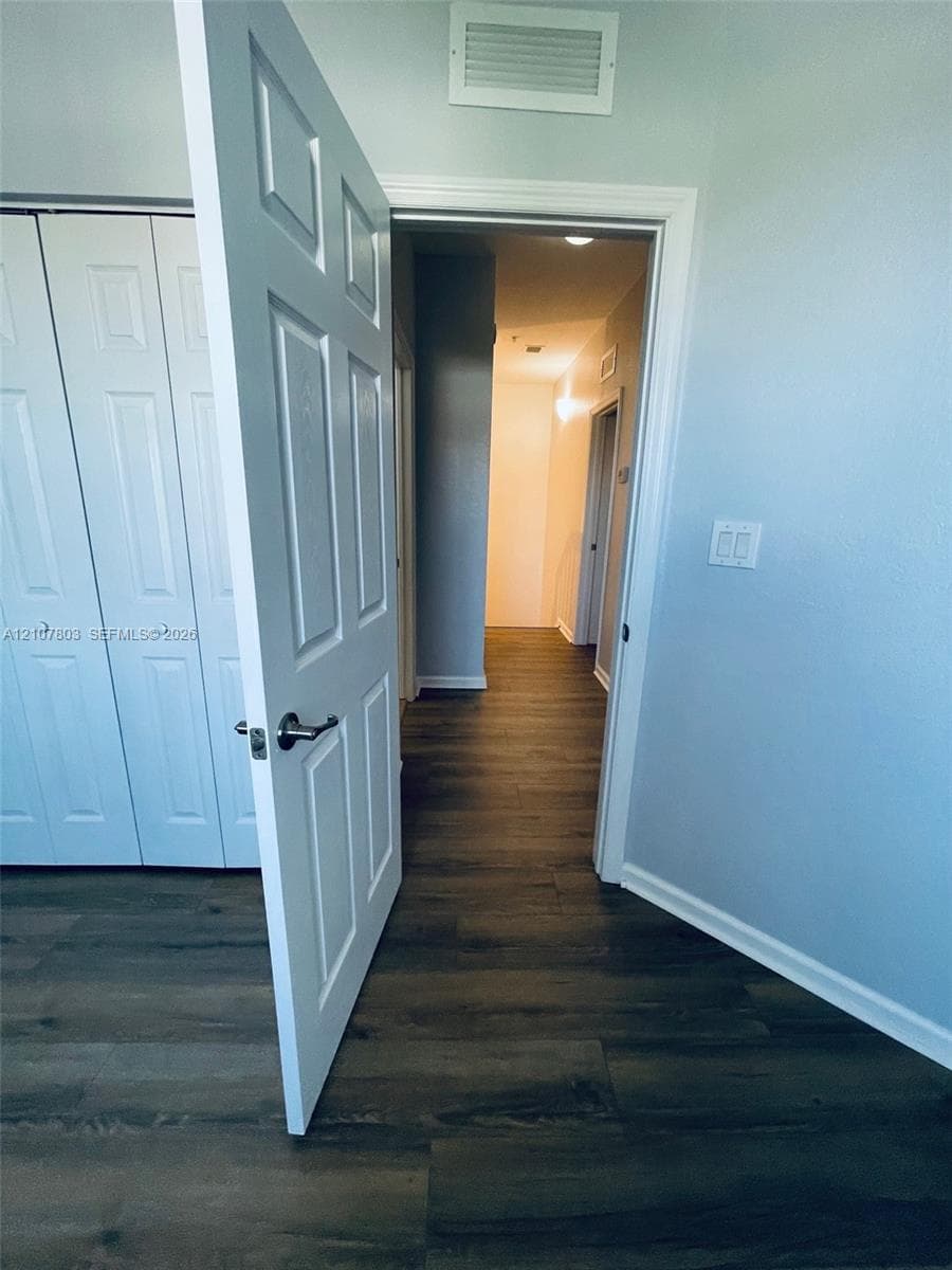 Wood-finish flooring, multi-panel interior door with satin nickel hardware, and bi-fold closet doors