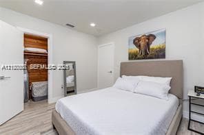 Wood-finish flooring, recessed lighting, and interior walk-in closet with natural wood shelving