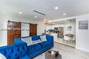 Open-concept interior featuring wood-finish flooring, recessed lighting, and sliding wood barn doors