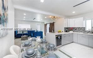Kitchen featuring white high-gloss cabinetry, stone-finish countertops, tile backsplash, built-in beverage refrigerator, and white tile flooring