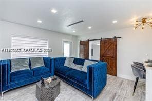 Wood-finish flooring, recessed lighting, and dual wood-paneled sliding barn doors