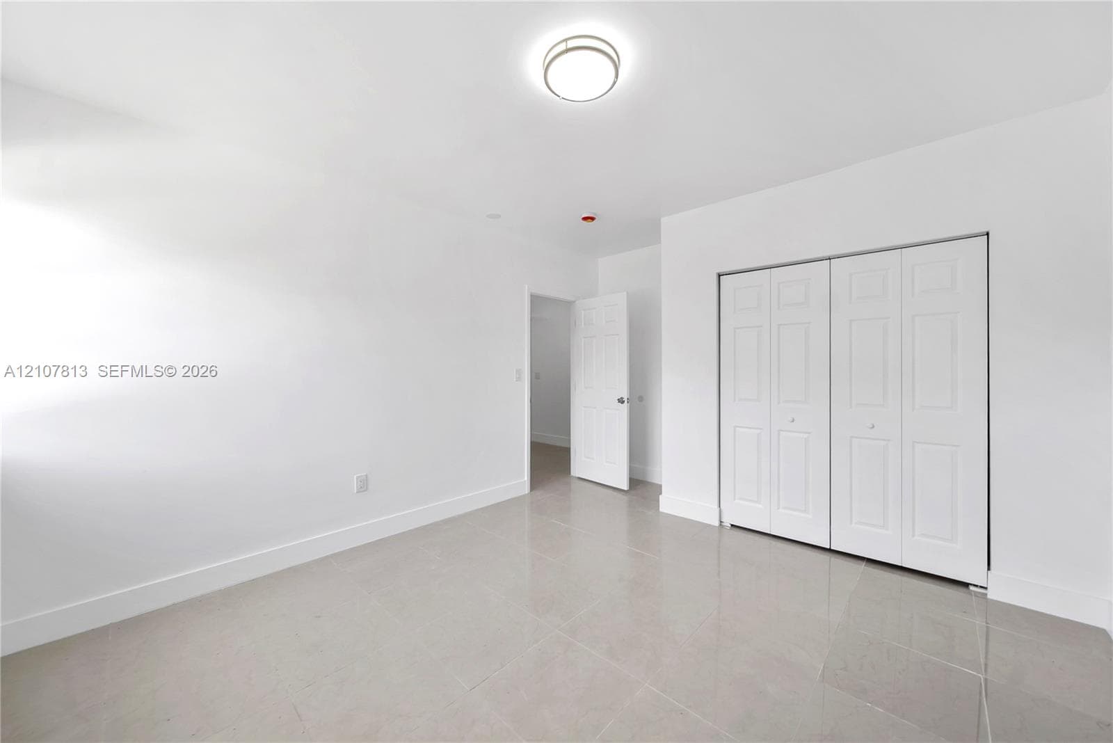 Neutral-toned ceramic tile flooring, crisp white walls, flush-mount dome lighting, and white six-panel folding closet doors