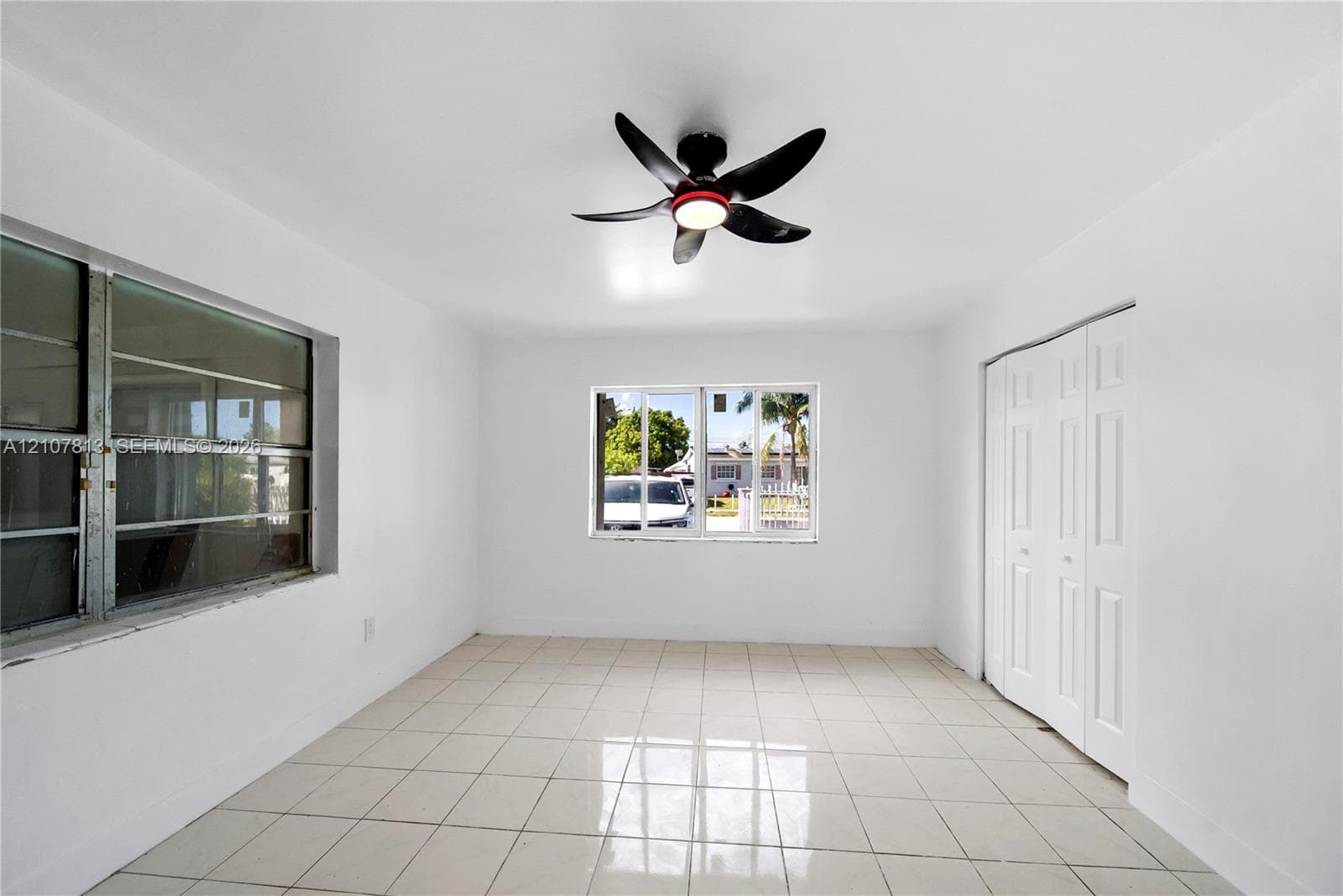 Interior space featuring polished ceramic tile flooring, dual-pane aluminum windows, and a modern ceiling fan with integrated lighting, complemented by a built-in bifold closet