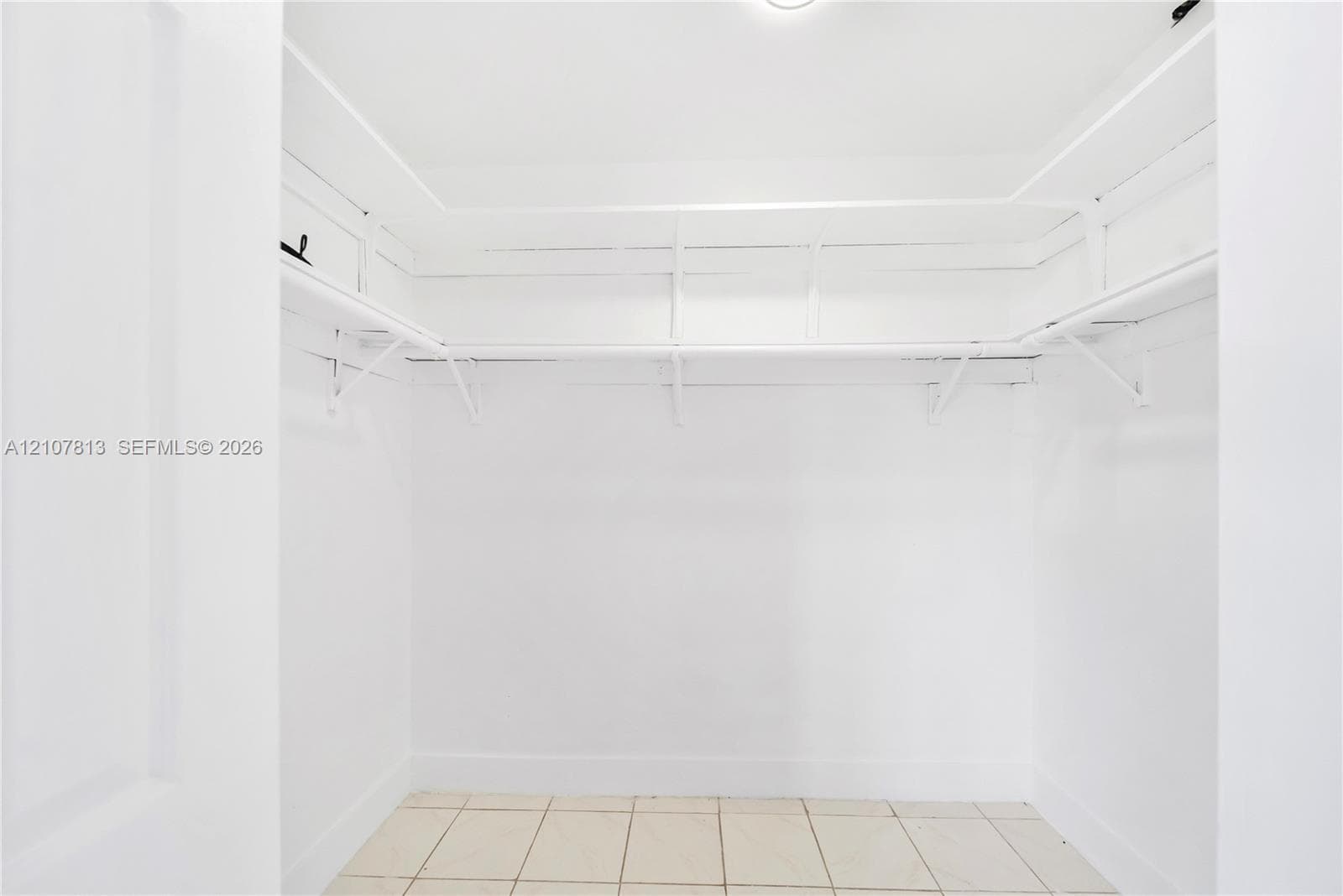 Walk-in closet featuring white walls, built-in shelving, integrated clothing rods, and tile flooring
