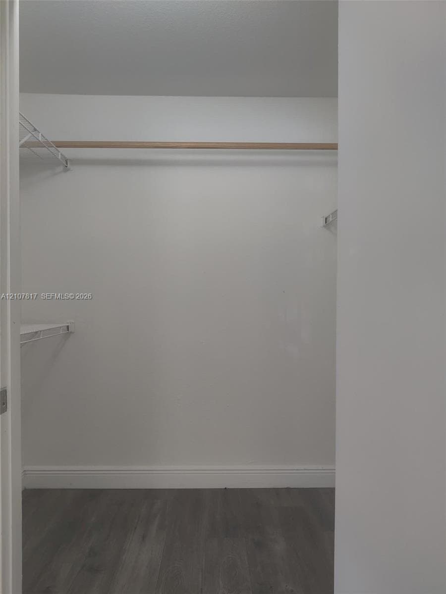Storage space featuring wood-finish flooring, a full-width hanging rod, and wire shelving