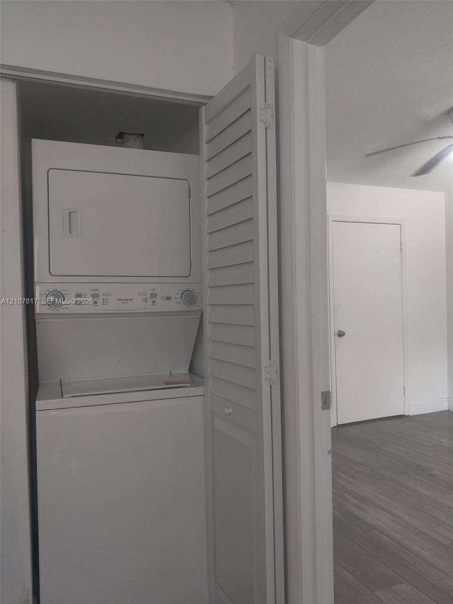 Laundry closet featuring a white stacked washer and dryer unit enclosed by louvered bi-fold doors