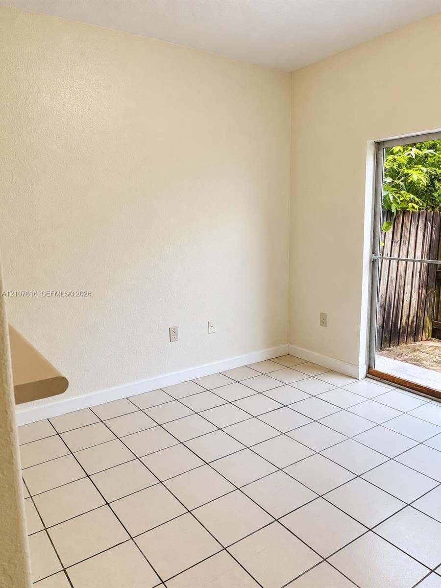 Neutral-toned interior featuring square ceramic floor tiling and a sliding glass door with exterior access