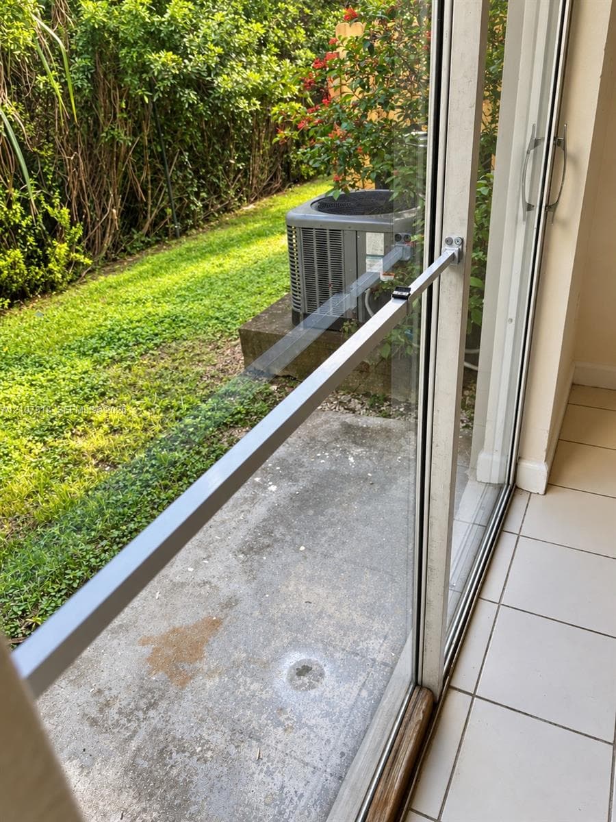 Sliding glass door featuring a metal security bar and white ceramic tile flooring