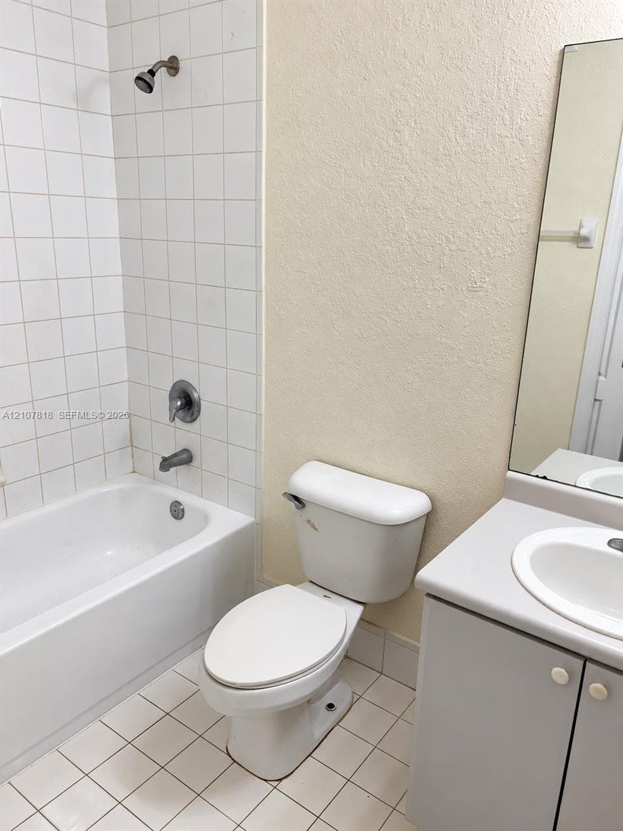 Bathroom featuring a tub-shower combination with white ceramic tile surround, integrated vanity cabinet with a solid surface countertop and undermount sink, and a wall-mounted mirror
