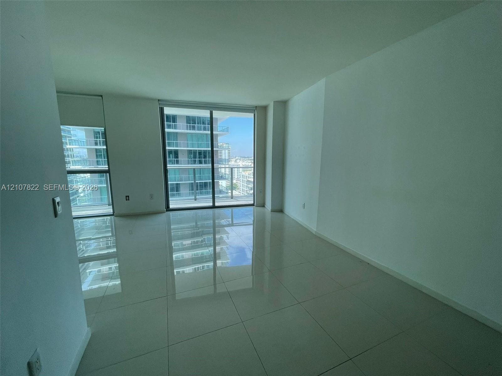Large-format tile flooring, floor-to-ceiling glass sliding doors, and access to a private balcony