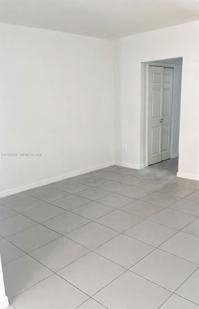 Neutral-toned tile flooring and white walls featuring a classic six-panel bi-fold door