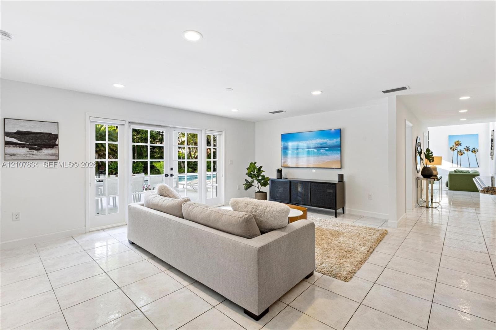 Open-concept living space featuring high-gloss tile flooring, recessed lighting, and multi-panel glass French doors