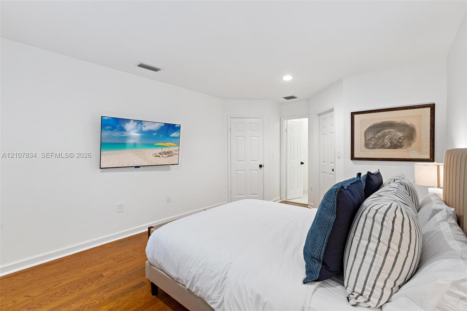 Interior space featuring wood-finish flooring, white walls, and interior doors with matte black hardware