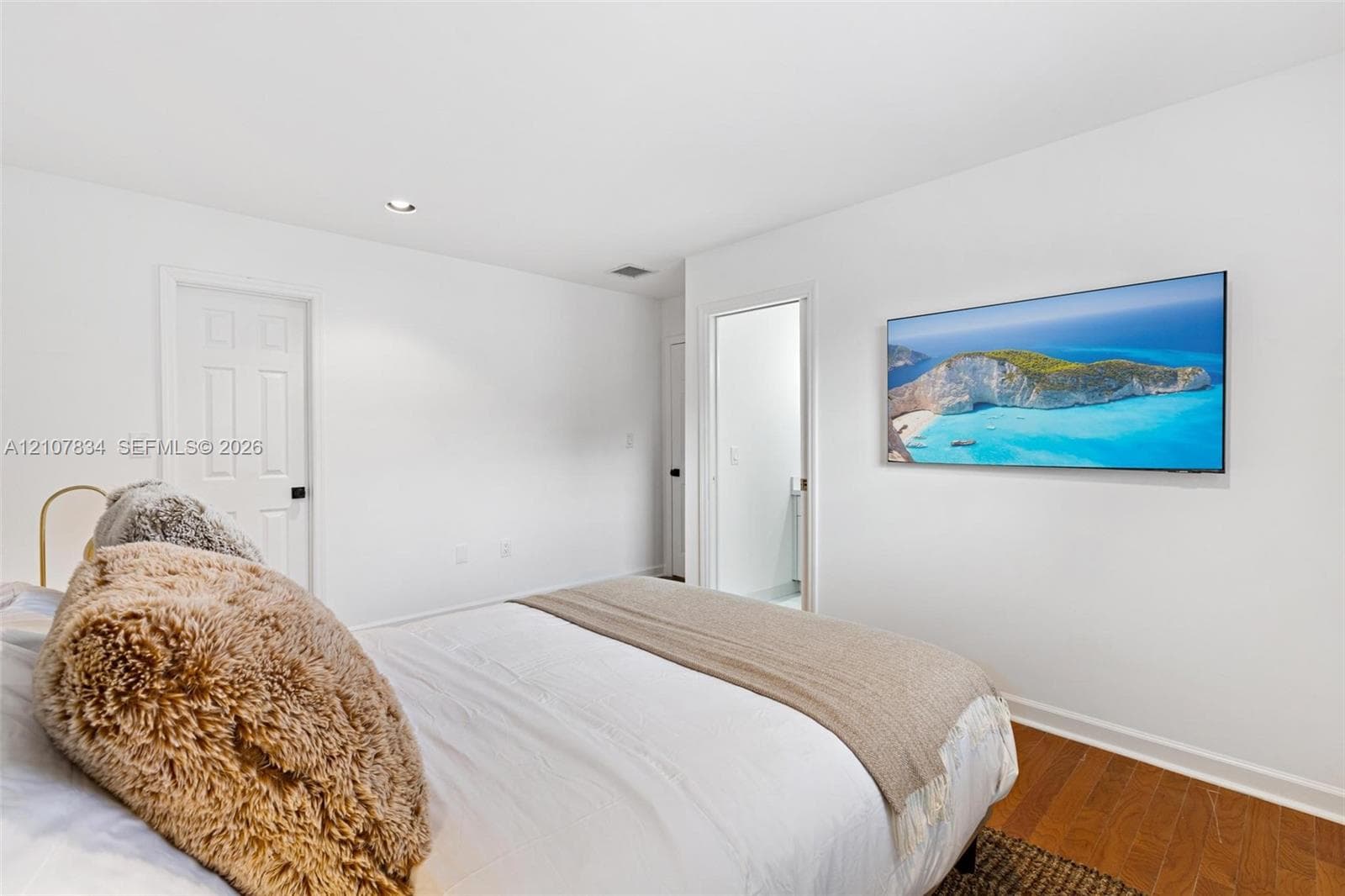 Neutral-toned interior featuring wood-finish flooring, recessed lighting, and white six-panel interior doors