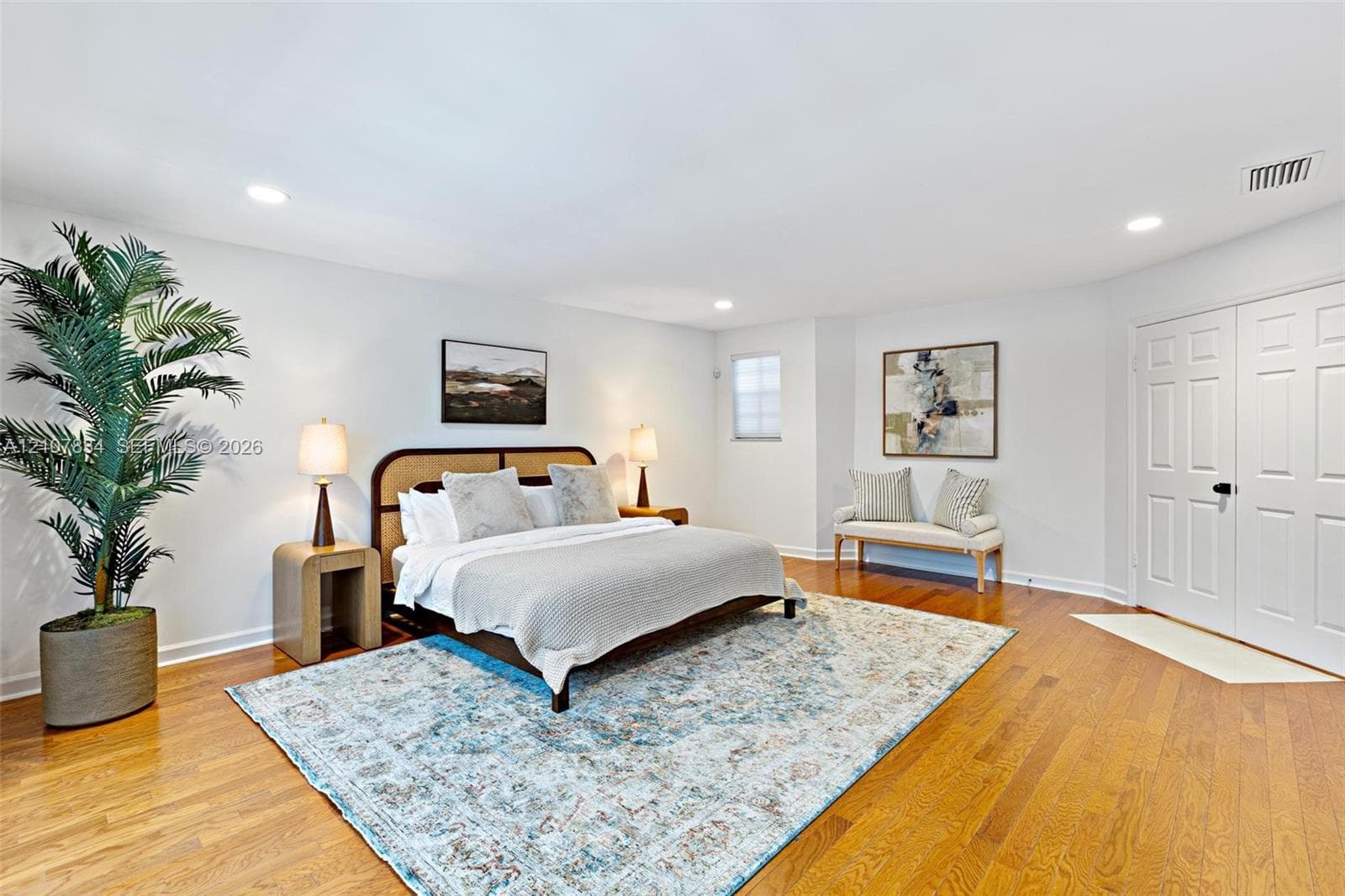 Spacious room featuring wood-finish flooring, recessed lighting, and double-panel doors