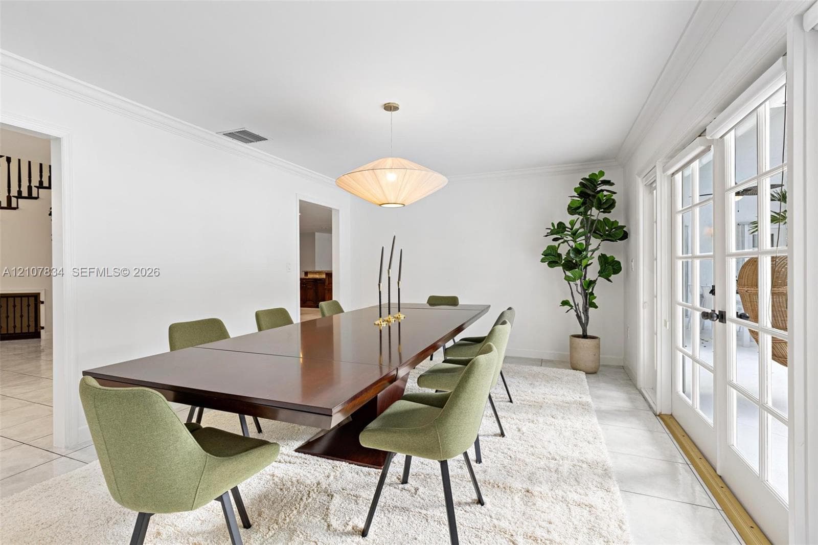 Light-filled interior featuring crown molding, large-format tile flooring, a modern pendant light fixture, and glass-paneled French doors