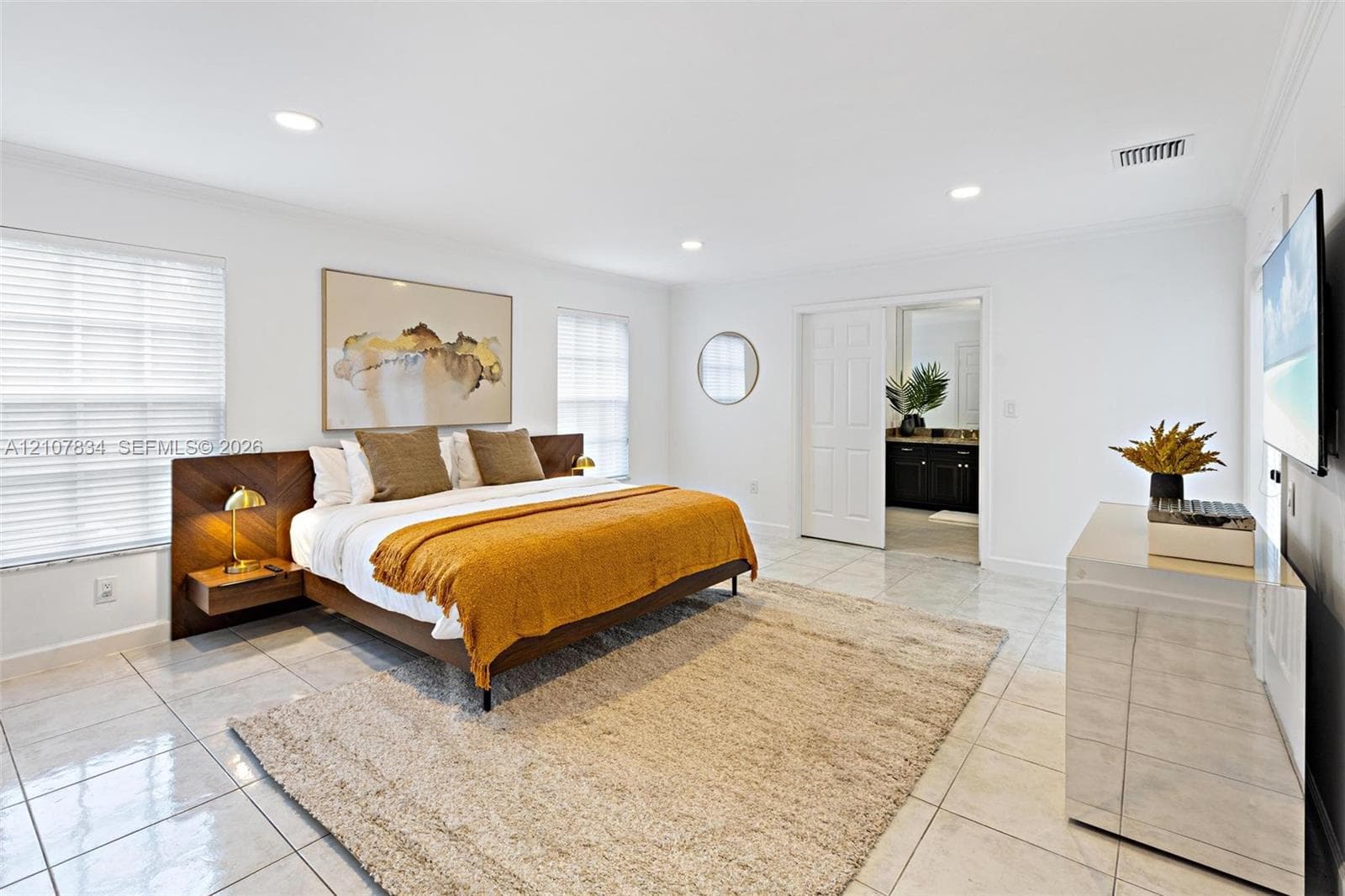 Spacious room featuring glossy tile flooring, recessed lighting, and a custom wood-panel headboard with integrated floating nightstands