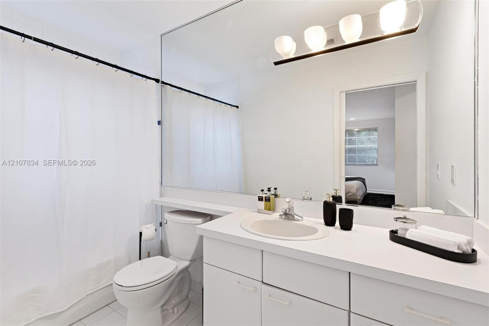 Full-width vanity mirror, vanity with integrated sink and countertop, and four-light horizontal fixture