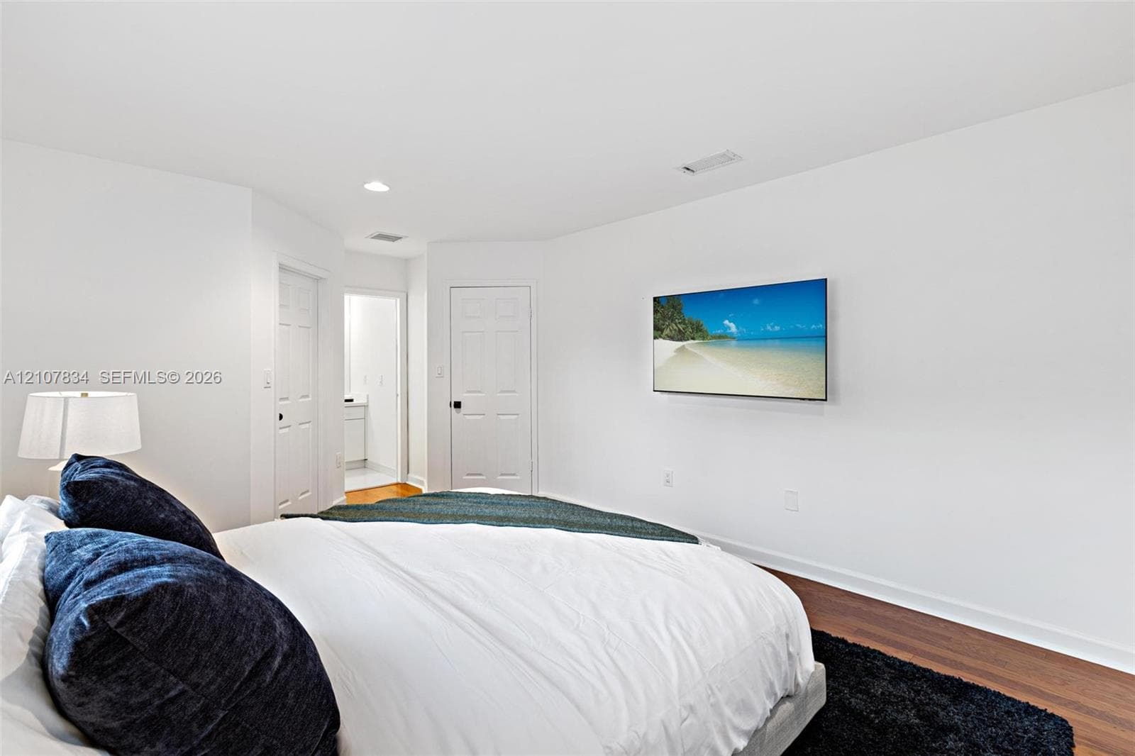Room featuring white walls, wood-finish flooring, recessed lighting, and six-panel interior doors