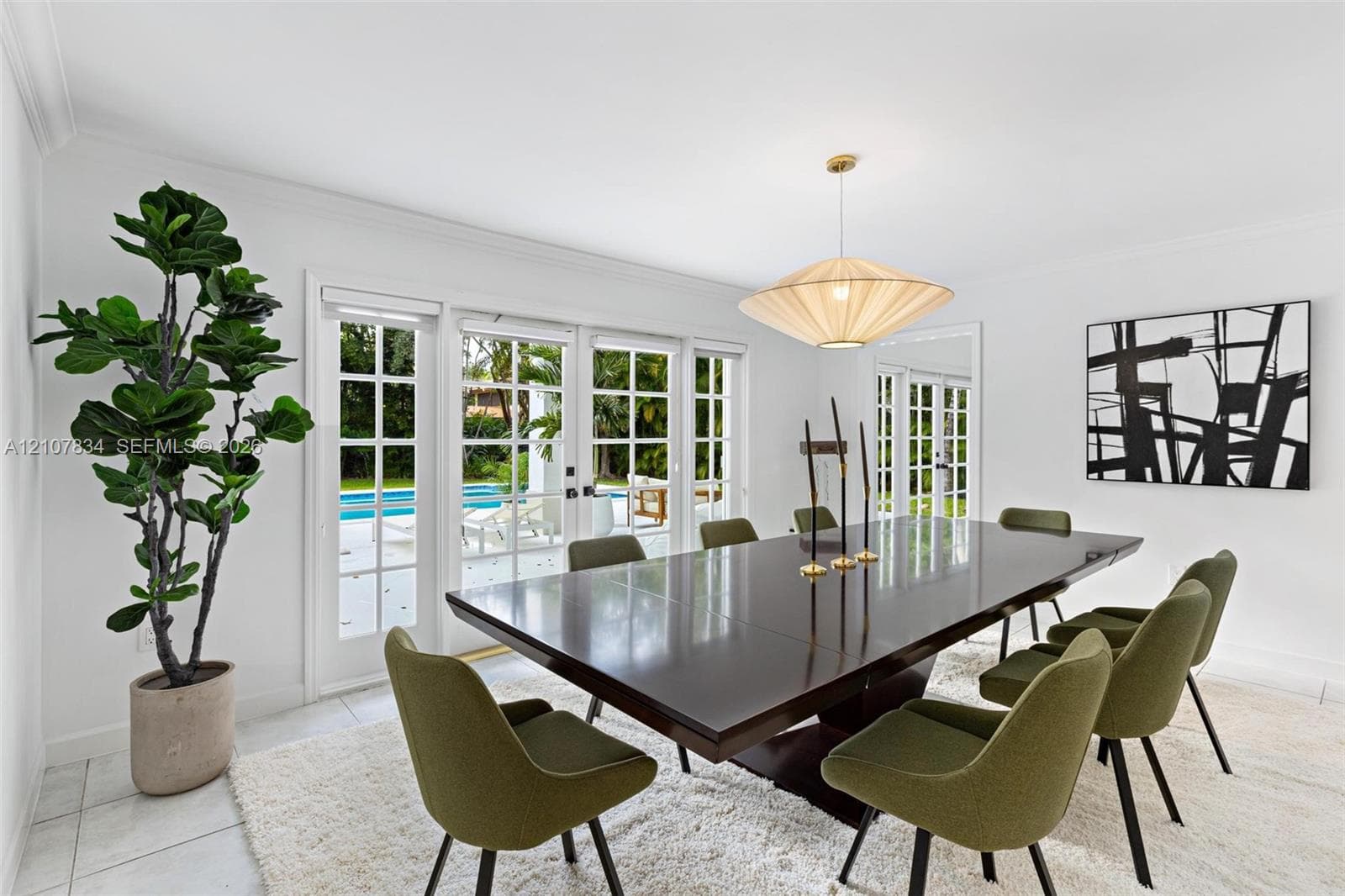 Dining area featuring neutral tile flooring, multiple sets of glass-paned French doors, and a decorative pendant light fixture
