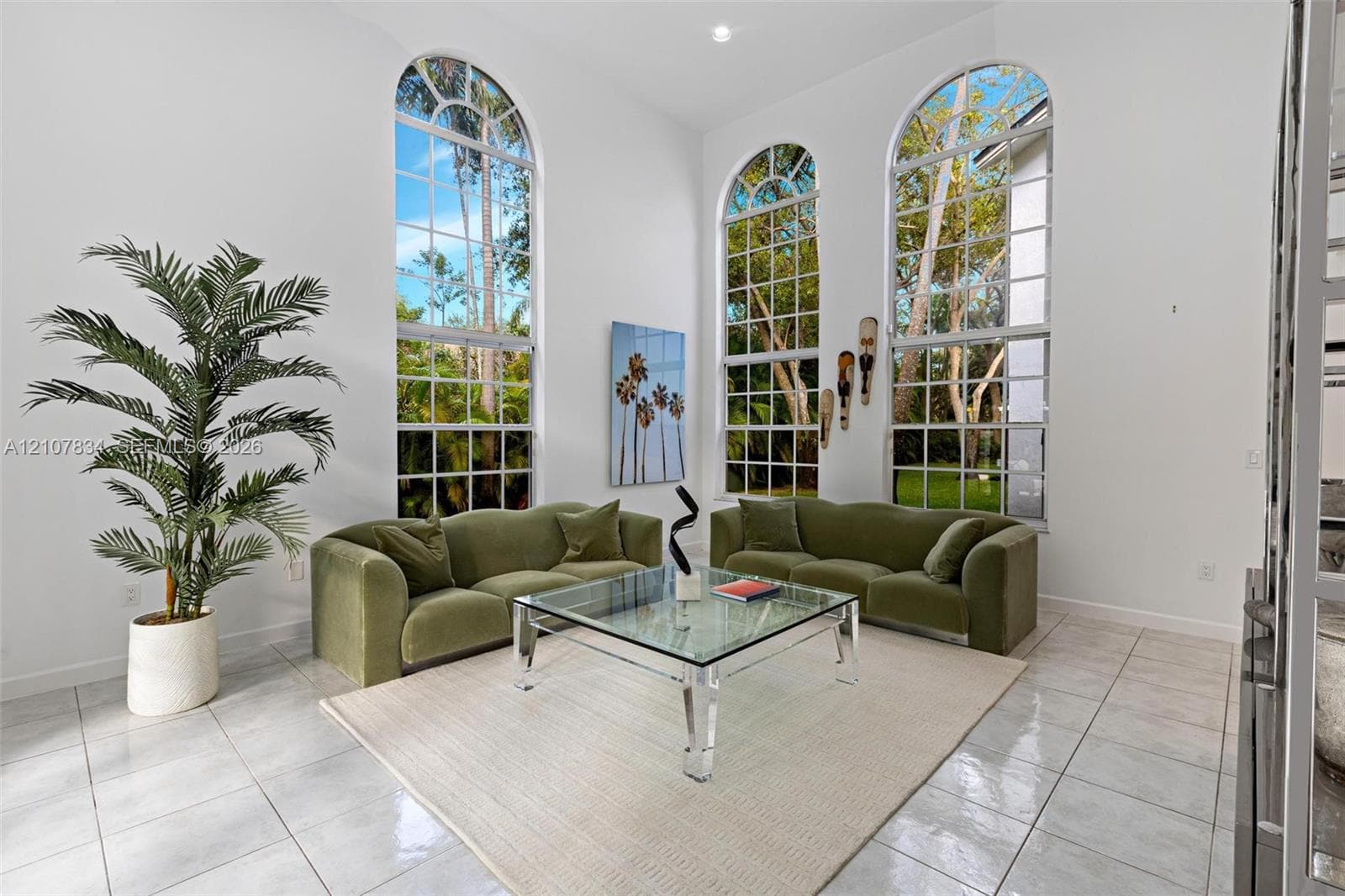 High-ceilinged room featuring oversized, arched, multi-pane windows and polished stone-finish floor tiling