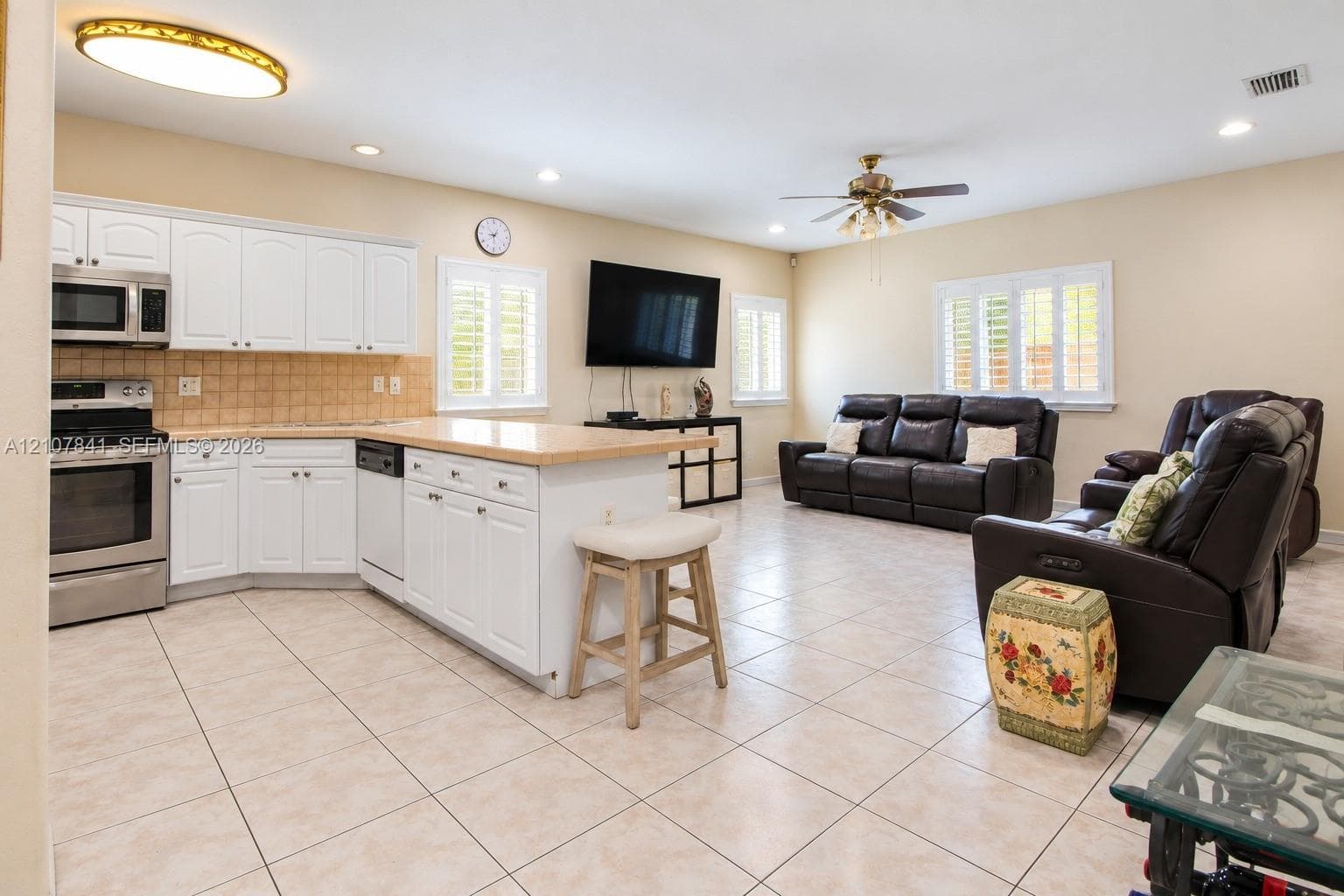 Open-concept interior featuring white cabinetry, a center island, ceramic tile flooring, plantation shutters, and recessed lighting