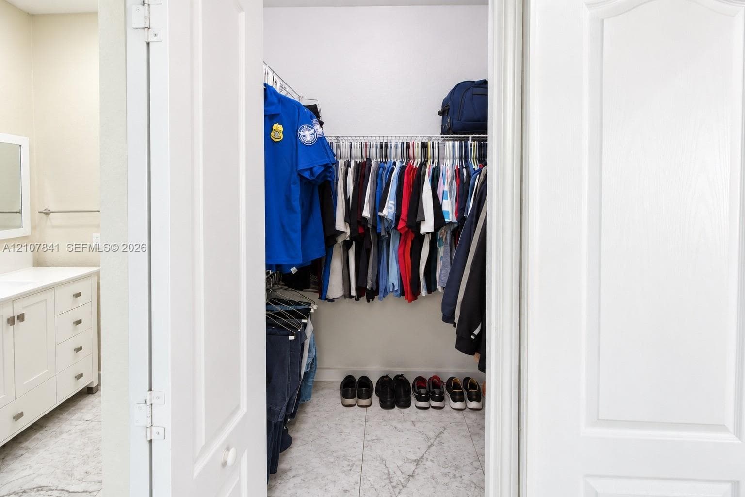 Walk-in closet featuring wire shelving, white cabinetry, and stone-finish flooring