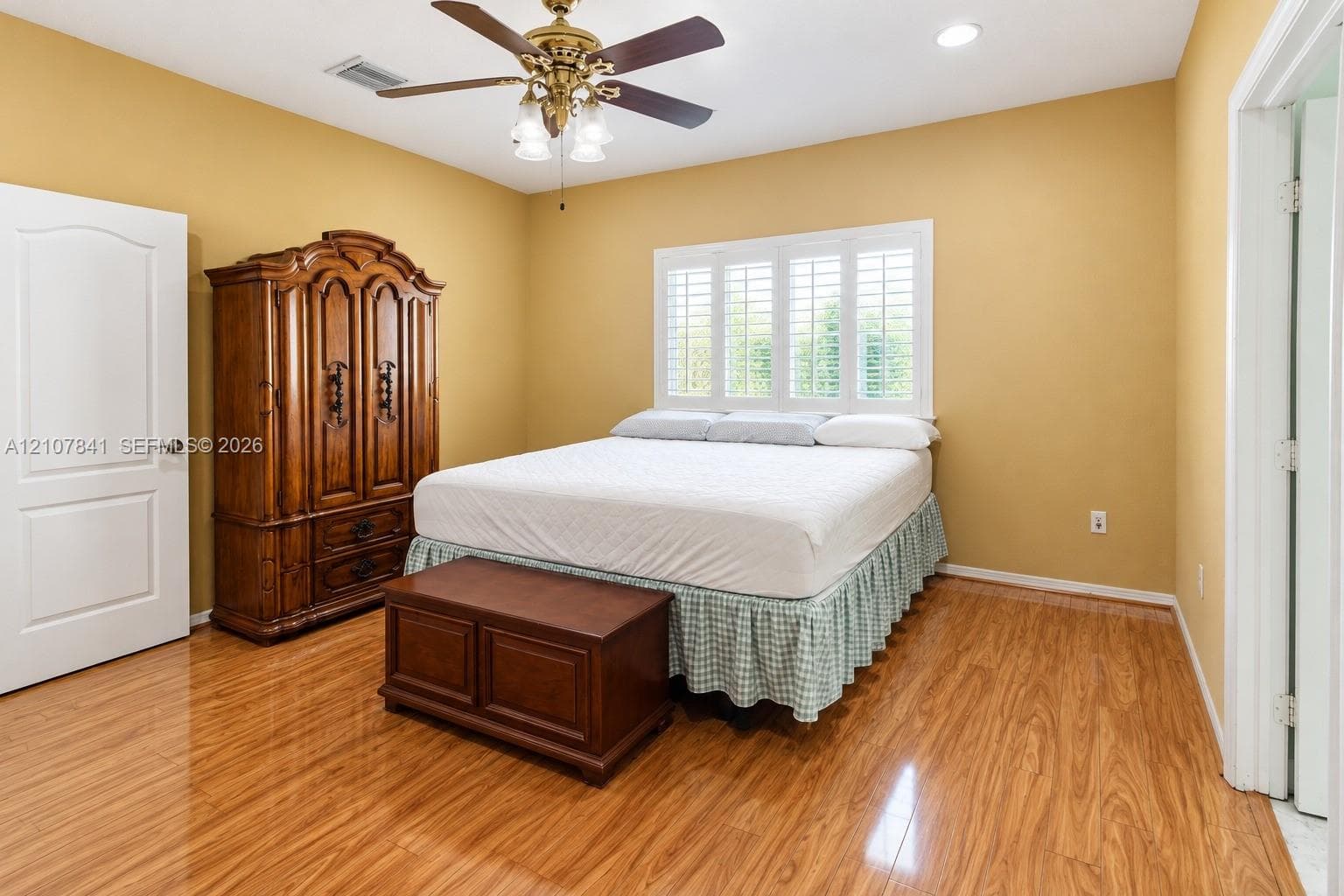 Wood-finish flooring, plantation shutters, and a ceiling fan with integrated lighting