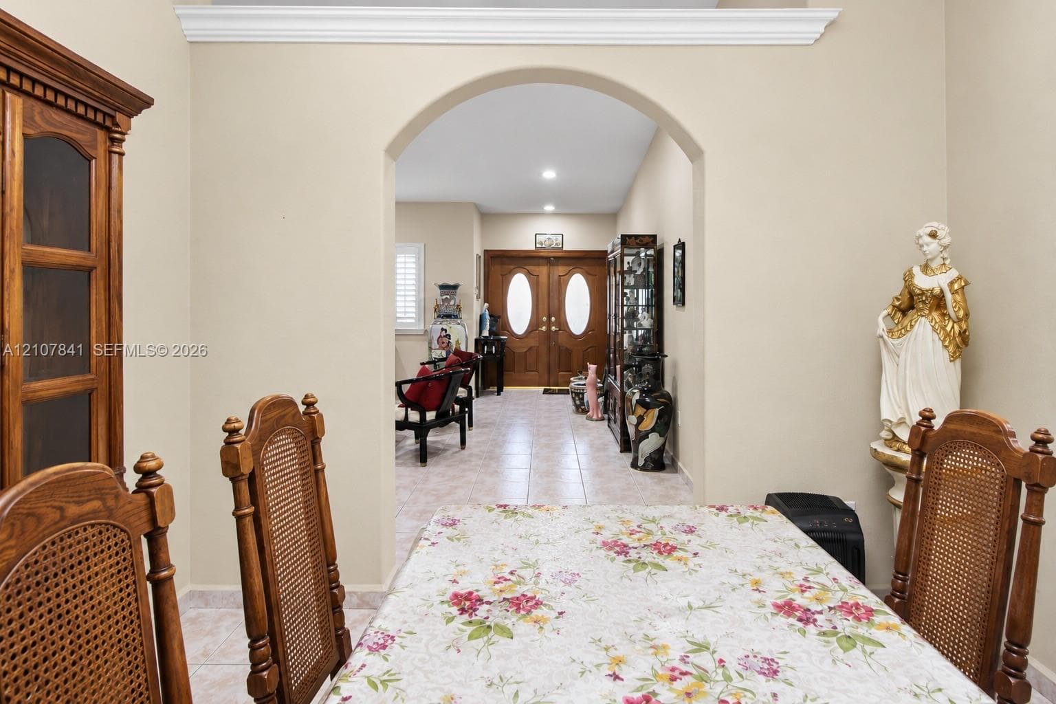 Interior space featuring a structural arched entryway, crown molding, double front doors with oval glass inserts, and tile flooring