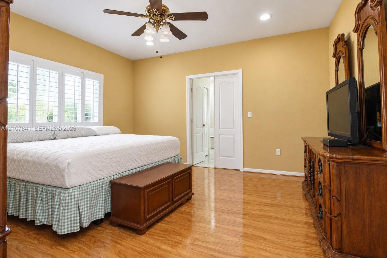 Wood-finish flooring, multi-panel interior doors, recessed ceiling lighting, a multi-blade ceiling fan with integrated lighting, and plantation-style window shutters