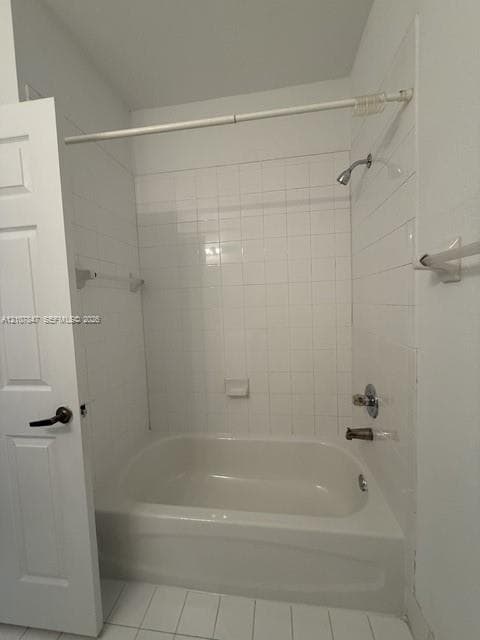 Bathtub and shower combination featuring a white tile surround, integrated soap dish, polished chrome fixtures, and a six-panel door