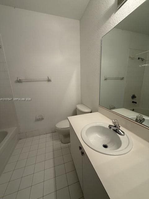 Bathroom featuring a vanity with integrated sink, chrome-finish faucet, large wall-mounted mirror, ceramic tile flooring, and a shower-tub combination