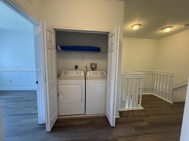 Laundry closet featuring bi-fold doors, white top-load washer and dryer, wire shelving, wood-finish flooring, and white spindle railing
