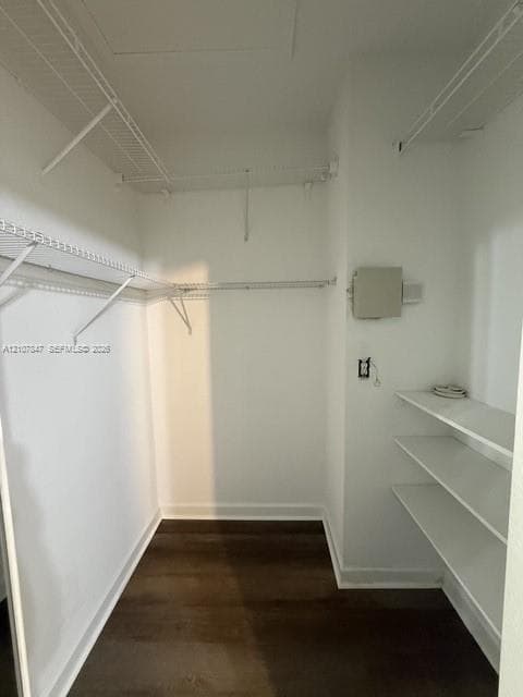 Storage space featuring white wire shelving, tiered built-in shelving, and wood-finish flooring