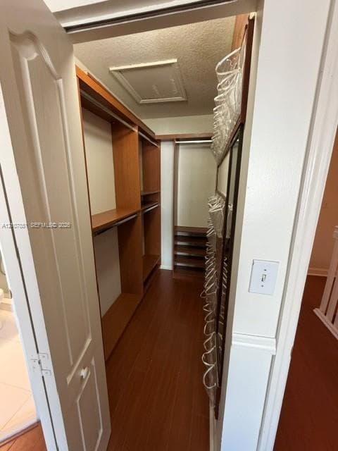 Walk-in closet featuring wood-finish flooring and custom built-in wood shelving with integrated hanging rods