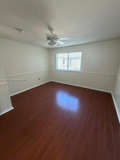 Room featuring wood-finish flooring, chair rail molding, a neutral color palette, and a ceiling fan with integrated lighting