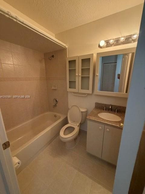 Bathroom featuring a tile-surround bathtub, vanity with stone-finish countertop and integrated sink, wall-mounted cabinetry, and four-bulb overhead vanity lighting