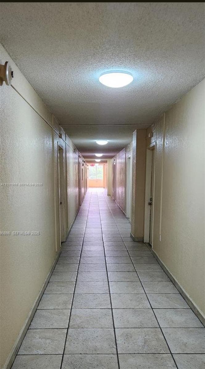 Interior hallway featuring tile flooring, smooth-finish walls, and ceiling-mounted flush lighting