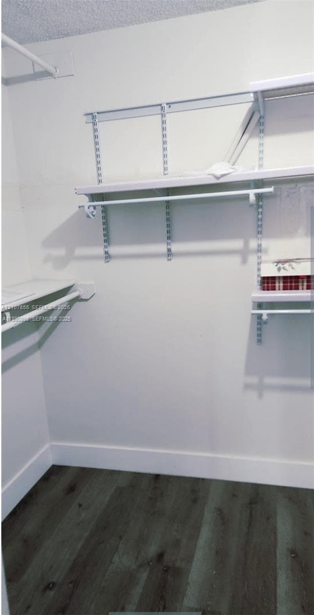 Walk-in closet featuring wood-finish flooring and adjustable white wire shelving units with integrated hanging rods