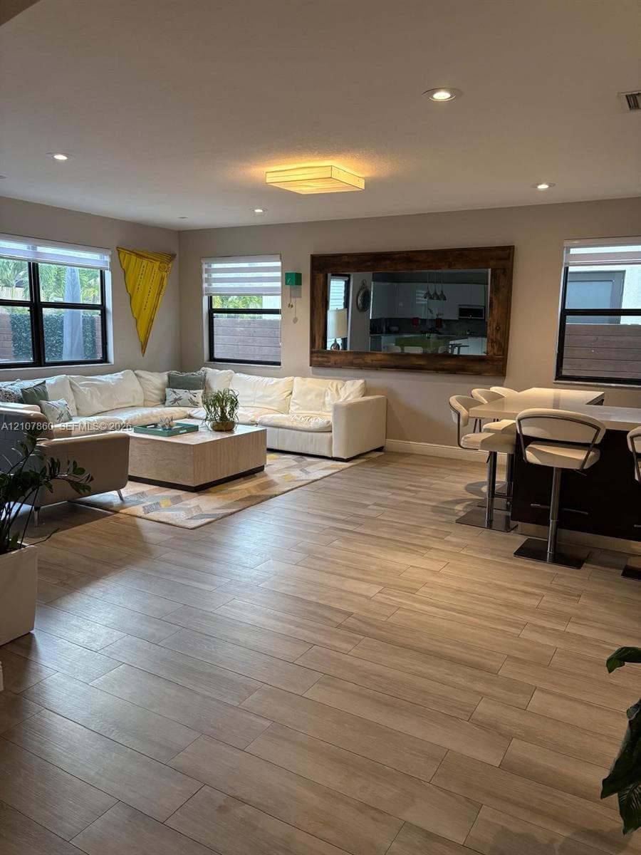 Open-concept interior featuring wood-finish tile flooring, recessed lighting, and a large wall-mounted mirror with a wood frame
