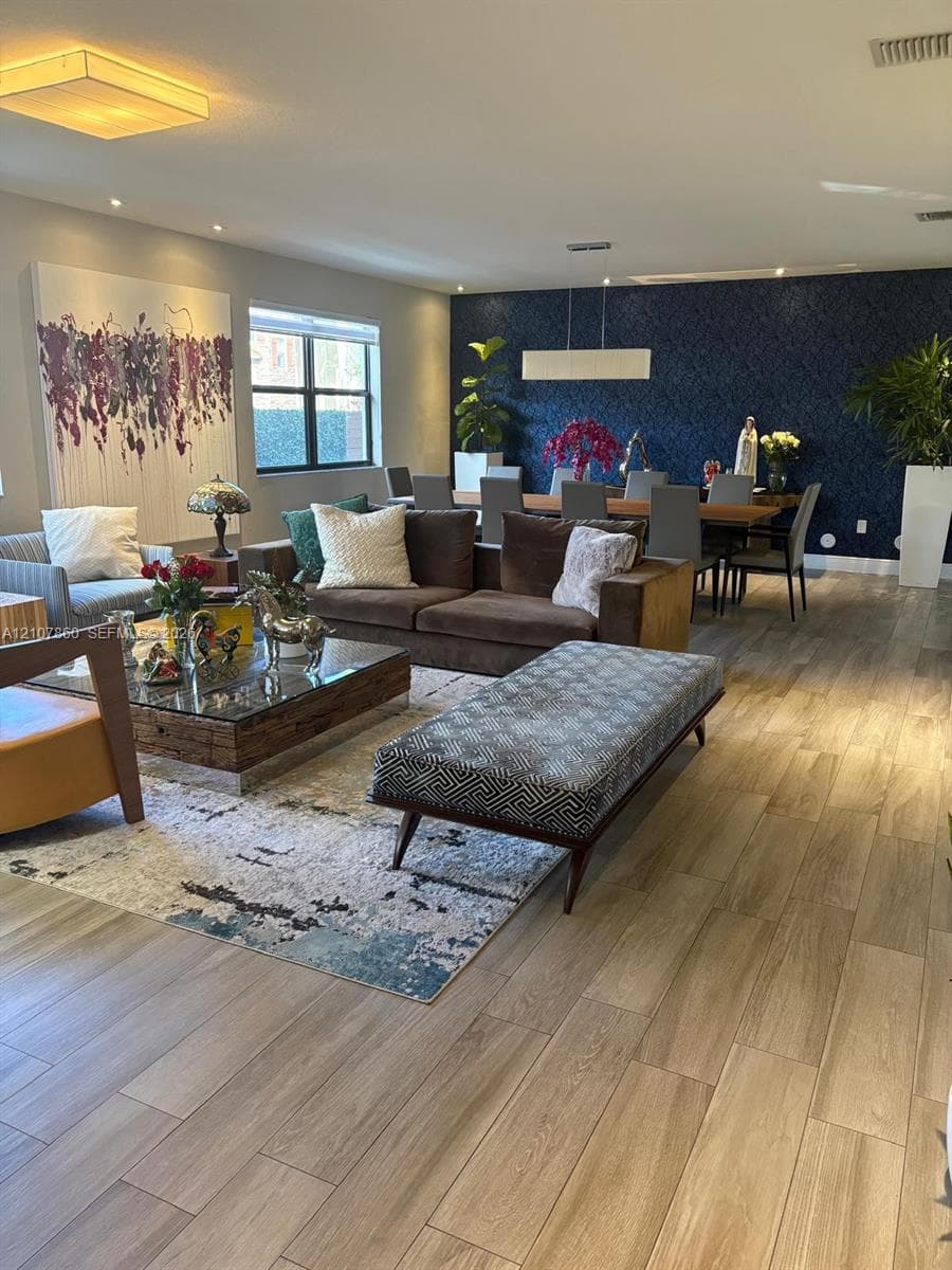 Open-concept interior featuring wood-finish tile flooring, recessed lighting, and a prominent dark blue patterned accent wall