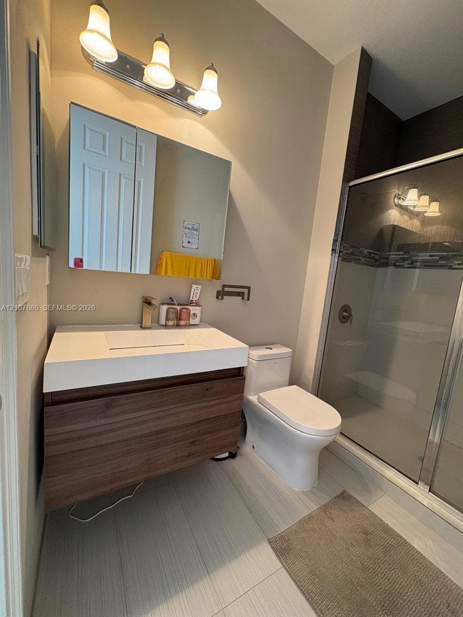 Modern floating wood-finish vanity with integrated sink, three-light vanity fixture, dual-panel medicine cabinet, and glass-enclosed shower with tiled surround
