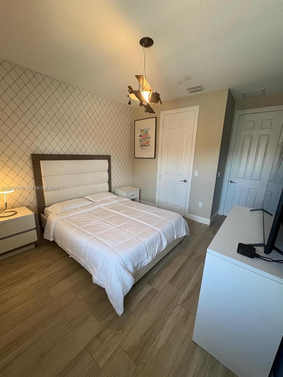 Wood-finish flooring, patterned accent wall, and multi-panel interior doors