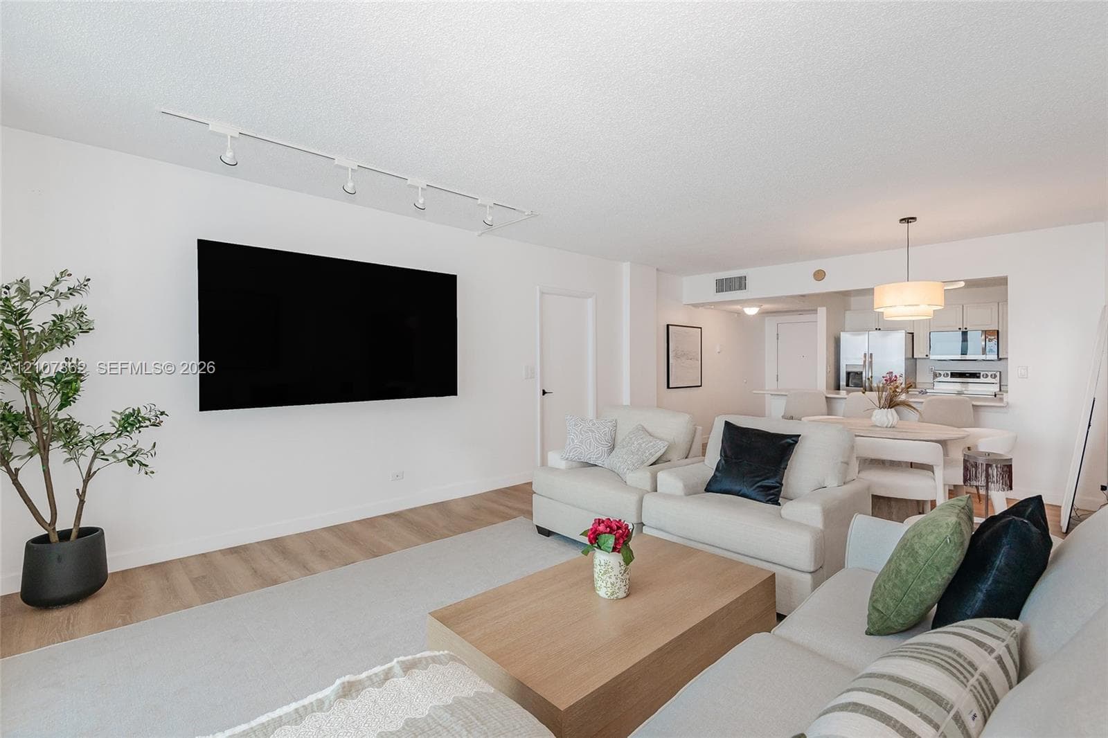 Living area featuring wood-finish flooring, white walls, and adjustable track lighting