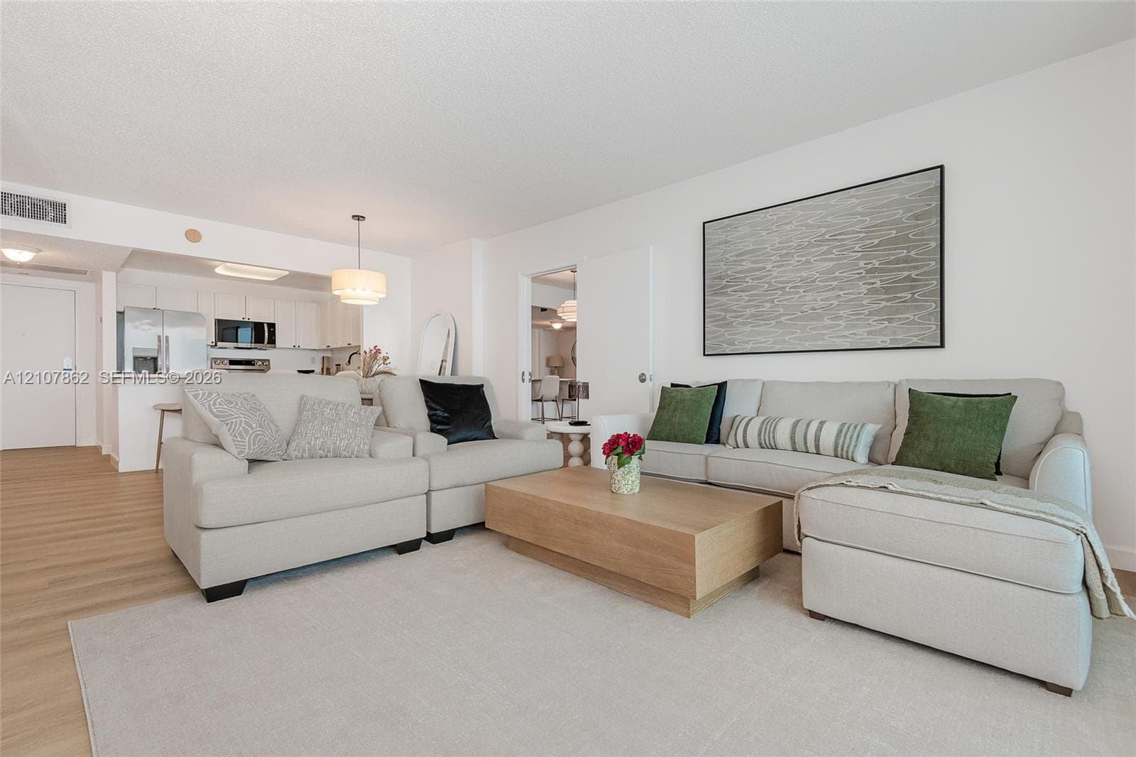 Open-concept floor plan featuring wood-finish flooring, white cabinetry, integrated recessed lighting, and a neutral color palette